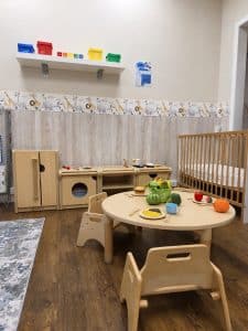 A cot and the home corner in the Little Acorns room